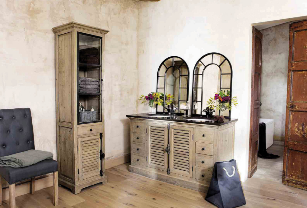 Salle de bains rétro avec meuble en bois vieilli, double vasque, miroirs à montants cintrés et ambiance naturelle aux accents vintage.