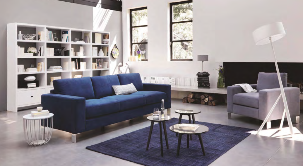 Un salon moderne qui adopte le bleu avec un canapé moderne, pièce maitresse d'un intérieur sobre à prédominance blanche